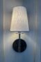 Thin sconce with white lampshade on blue wall