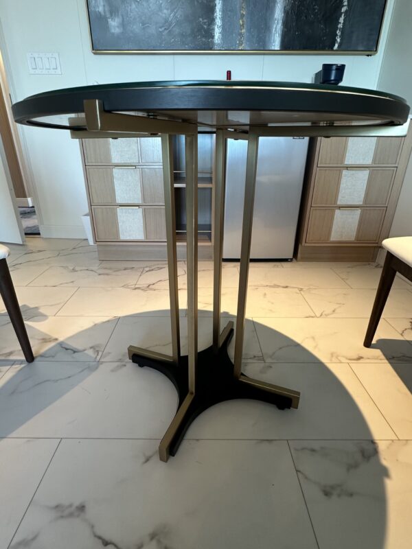 Round dark wood table with four brass legs in the center