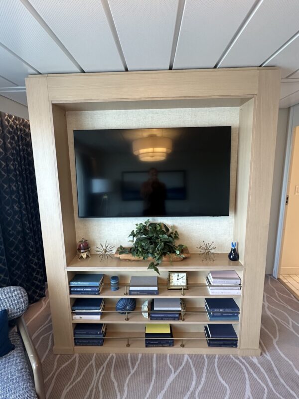 Shelving unit with flat screen tv and three shelves for books and plants made of light wood