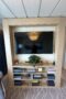 Shelving unit with flat screen tv and three shelves for books and plants made of light wood